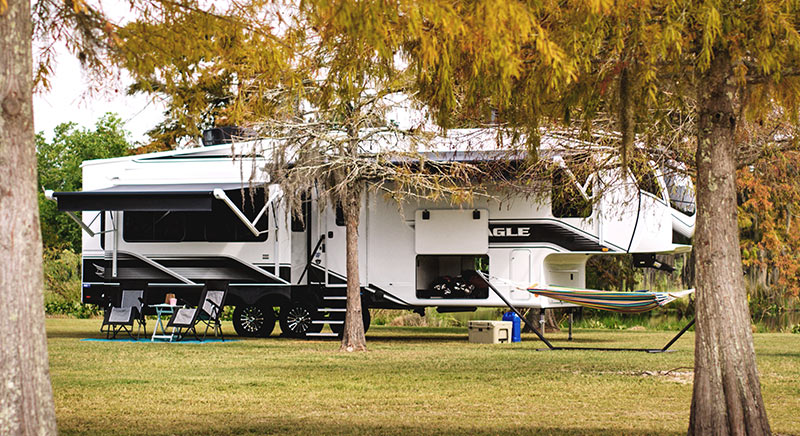 Photo of Jayco Eagle fifth wheel parked behind some trees.