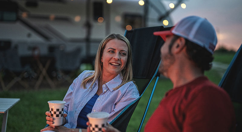 Photo of a couple outdoors with a Jayco Jay Feather AIR in the background.