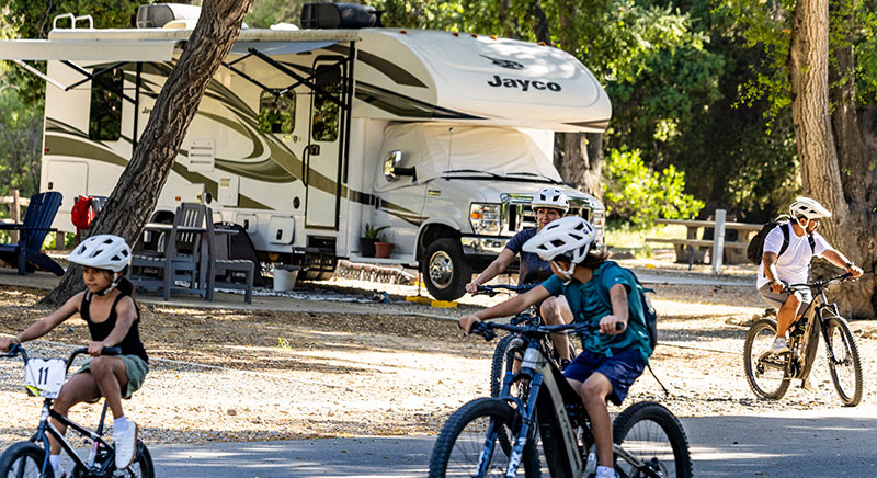 Photo of a Jayco Greyhawk Class C motorhome at a campground with kids riding bikes nearby.