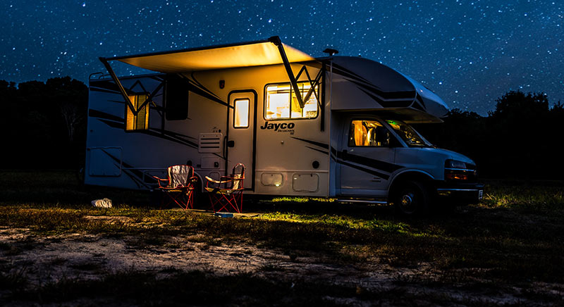 Photo of a Jayco Redhawk class C motorhome at night with lights on.